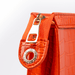 Close-up of a red handbag with a gold zipper pull on a white background