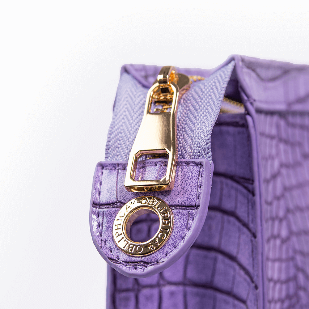 Close-up of a purple textured handbag with a gold zipper pull on a white background