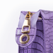 Close-up of a purple textured handbag with a gold zipper pull on a white background